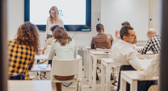 diverse group of creative people having training at the classroom by experienced middle-aged female business trainer