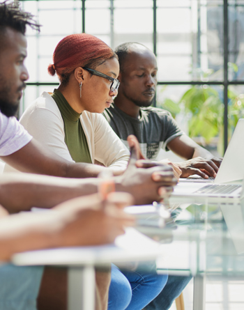 employees working at computer together, discussing content and training